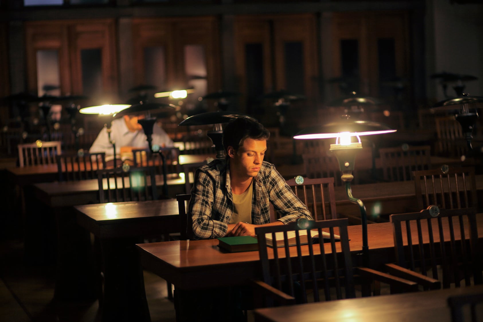 Young man reading in library at night