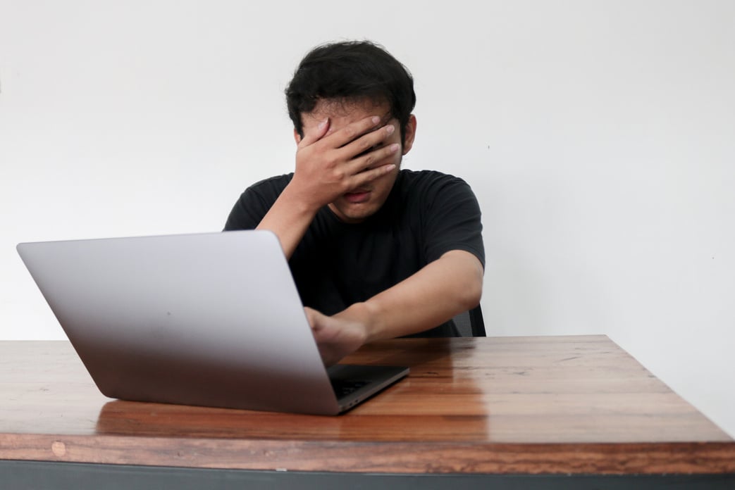 Young asian man hiding his face with hand because shocked an